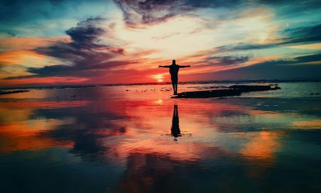 Life changes - Silhouette of person standing on rock surrounded by body of water.